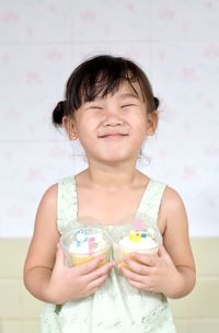 Portrait of cute girl standing against wall