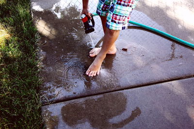 Low section of man cleaning legs on footpath