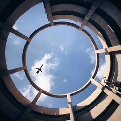 Directly below shot of silhouette airplane seen through building