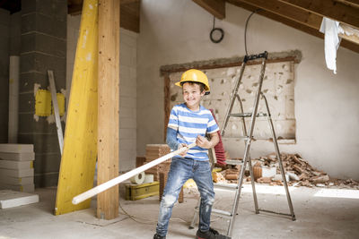 Portrait of cute boy holding while standing against ladder