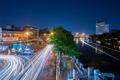 Light trails on road in city against clear sky at night