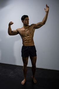 Shirtless muscular man standing against wall