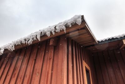 Low angle view of icicles on roof of building against sky