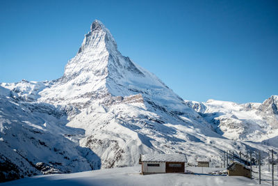 Scenic view of snowcapped mountains against clear blue sky