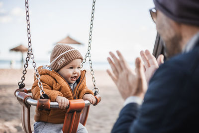 Midsection of man swinging at playground