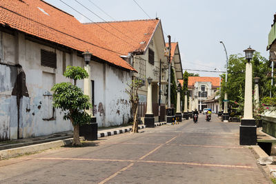 Road by buildings in city against sky