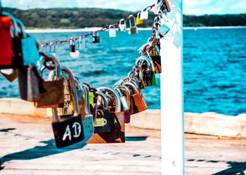 Close-up of padlocks on railing against sea