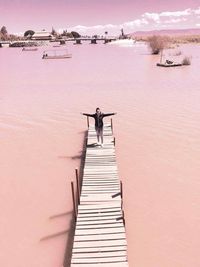 High angle view of woman with arms outstretched on pier by lake at chapala