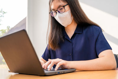 Midsection of woman using phone while sitting on table