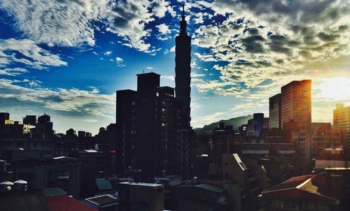 Buildings in city against cloudy sky