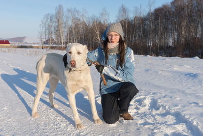 The girl sat down with a big white shepherd dog on the side of the road amid the forest.
