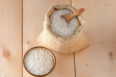 High angle view of sack and bowl with rice on table