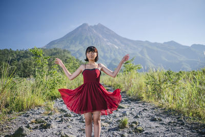 Full length of woman standing on rocks against mountain