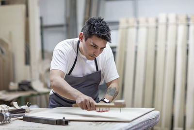Artist giving design to wood through traditional method while standing at workshop