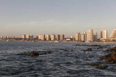 Sea by cityscape against sky