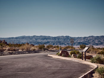 Road by mountains against clear sky