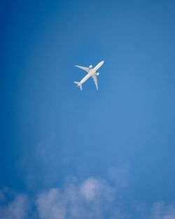 Low angle view of airplane flying against blue sky