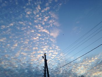 Low angle view of power lines against cloudy sky