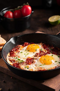 Israel traditional food shakshouka with micro greens in a cast-iron pan close up