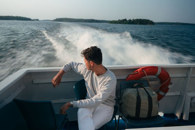 Rear view of man sitting on boat in sea