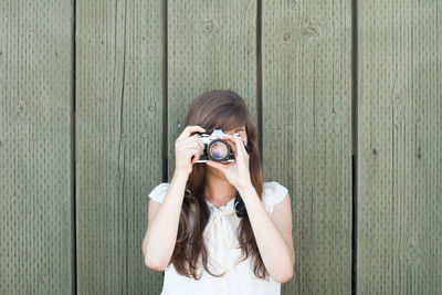 Woman photographing against wooden planks