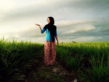 Rear view of young woman standing on field