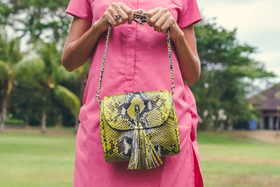 Midsection of woman holding pink while standing outdoors