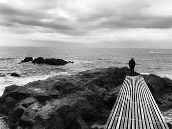 Man standing on sea shore against sky