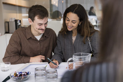 Happy couple smiling while signing agreement at desk in real estate office