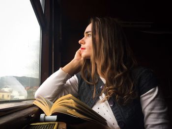 Young woman looking through window while traveling in train