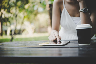 Midsection of woman using digital tablet at table