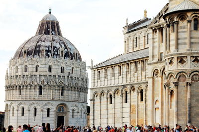 Tourists in front of church against sky