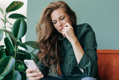 A beautiful red-haired woman looks at a message on her mobile phone.