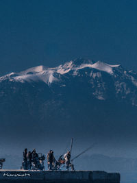 People on mountain by sea against sky