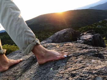 Low section of man on rock against sky