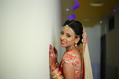 Side view of bride standing by wall in corridor