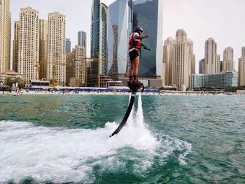 Man in sea by city against sky