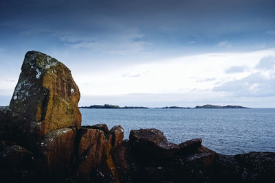 Rock formation on beach against sky