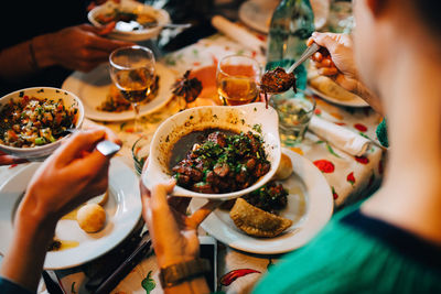 High angle view of women serving food from bowls while sitting at table in restaurant during brunch