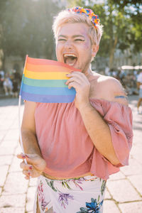 Happy gay man laughing with rainbow flag on sunny day