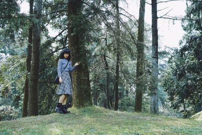 Full length of man standing amidst trees in forest