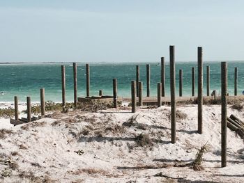 Wooden posts on beach against clear sky