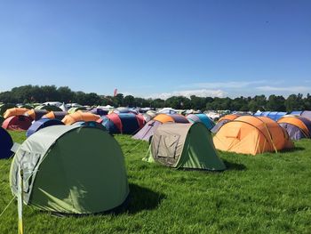 Tents on grass against blue sky