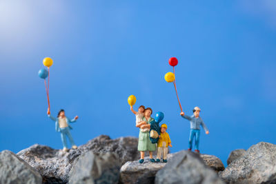 Low angle view of balloons on rocks against blue sky