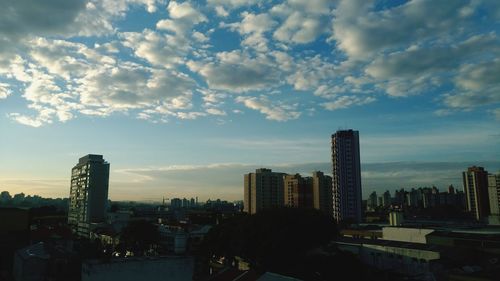 Modern buildings in city against sky during sunset