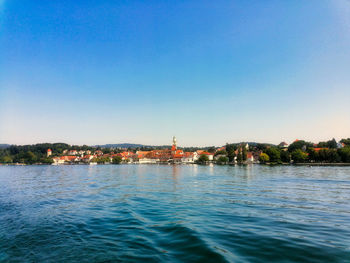 Sea by buildings against clear blue sky