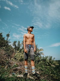 Full length of shirtless man standing against sky