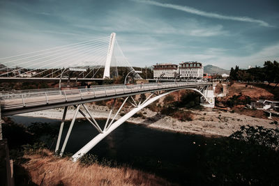 Arch bridge over river against sky in city