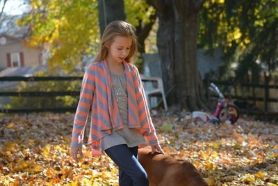 Blond girl walking with dog at back yard
