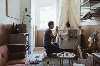 Male toddler playing with father in living room